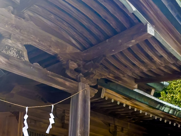 The rafters are pieces of wood spaced evenly across the bottom of the roof, and the joint between the central pillars is decorated with a flower-like design.