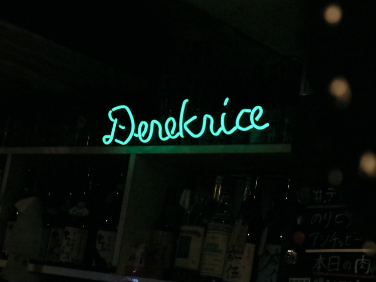 The neon sign of "Derekrice" above the counter lights up the store as a symbol of their friendship.