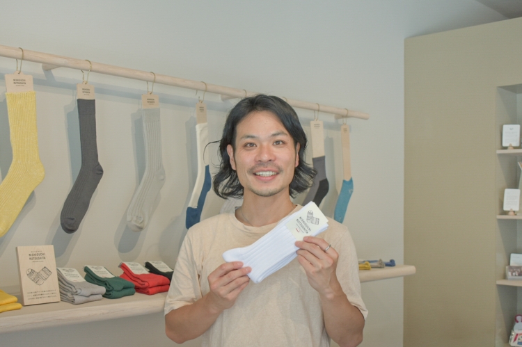 Ms. Nishiguchi is holding the "Egyptian Cotton Rib Socks," a classic pair of socks characterized by their unique elasticity.