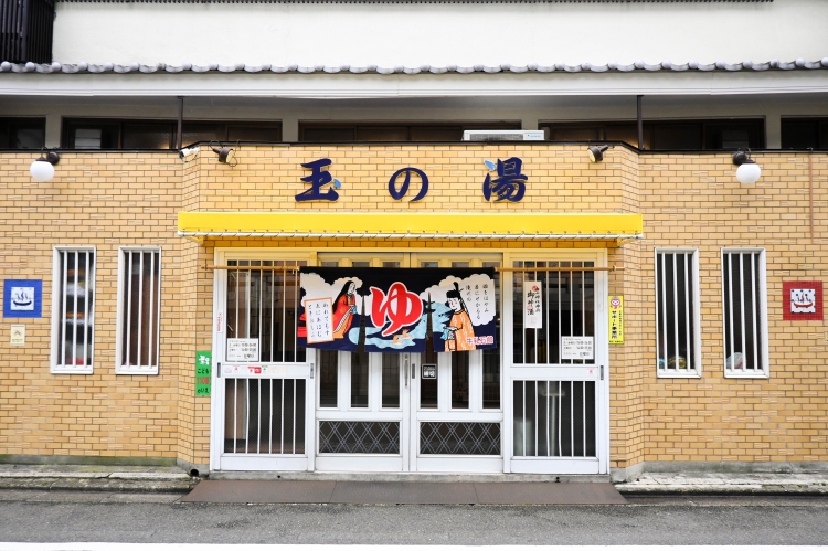 The exterior, with its yellow tiles and the words "Tama no Yu," is eye-catching.