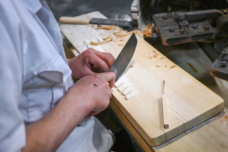 The mochi is rolled out thinly and then precisely cut into individual pieces to fit the baking mold.
