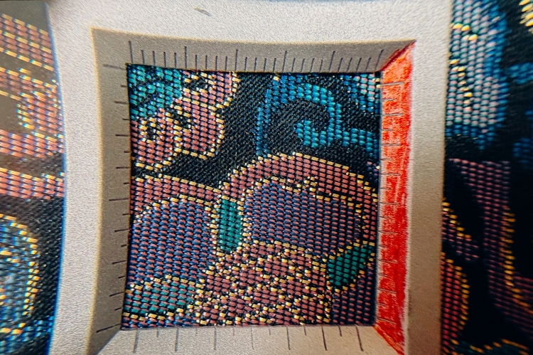 When viewed with a magnifying glass, it becomes clear that the fabric is woven from three different colored threads.