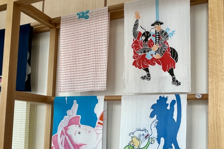 A tenugui (Japanese hand towel) with a rebus picture. The upper right corner shows an ant holding a sword, which means "thank you."