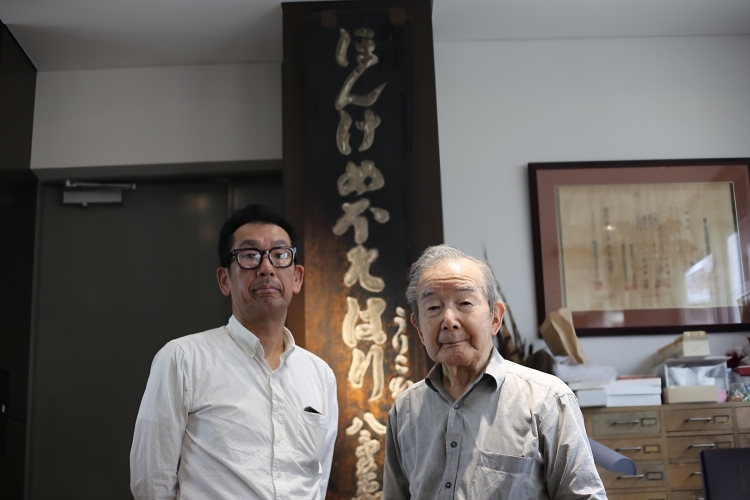 Yuji Mehoshi, the 20th generation, and Shinichi Mehoshi, the 19th generation. They still cherish and display the vintage sign.